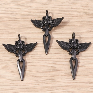 Vue détaillée de pendentifs croix rose gothique noire avec ailes sur surface en bois