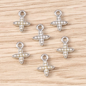 Detail view of silver cross charms with embedded white pearls for DIY jewelry making