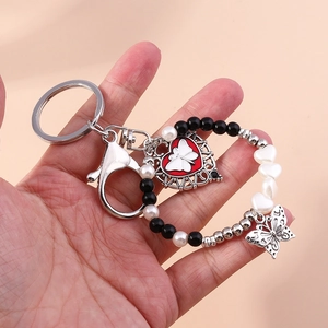 Detail of butterfly keychain with silver heart pendant, red charm and pearl beads