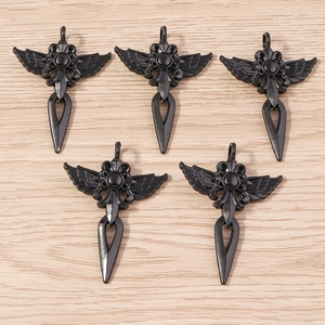 Détail de pendentifs croix gothiques en alliage noir avec ailes sur surface en bois