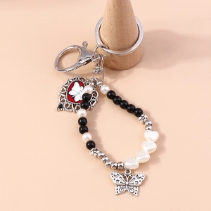 Close-up of butterfly butterfly hollow metal charm and red enamel heart on keychain