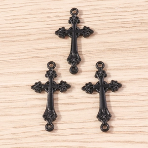 Détail de trois pendentifs croix gothiques noirs avec gravures sur fond de bois