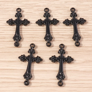 Gros plan de pendentifs croix rose noire en alliage sur un fond de bois clair