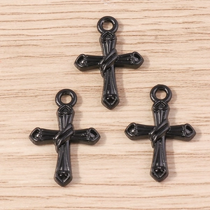 Détail de trois pendentifs croix gothiques en alliage noir sur un fond en bois clair