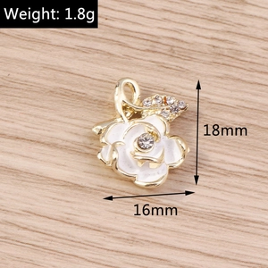 Detailed macro view of gold rose pendant with white enamel petals and sparkling rhinestones