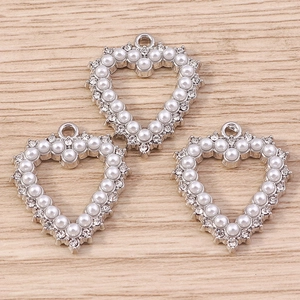 Macro shot of silver alloy heart pendants with pearl border and rhinestone accents