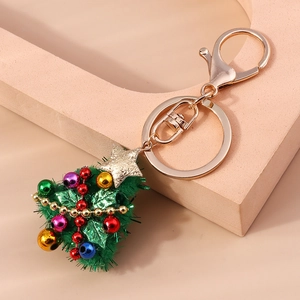 Plush Christmas tree keychain with colorful baubles and a gold star on a pink display