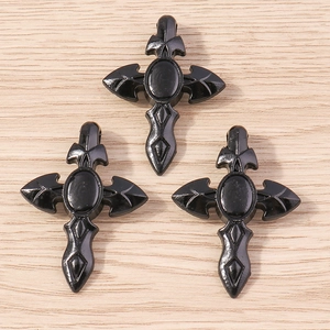 Détail macro de trois pendentifs croix gothiques noirs avec pierres sur fond de bois