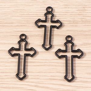 Trois pendentifs croix rose gothiques en métal noir avec boucles sur fond de bois naturel
