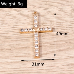 Detail view of a 49mm gold cross pendant with heart inlay and rhinestone accents