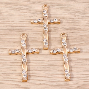 Macro detail of gold alloy cross pendants with clear rhinestones and spiral texture