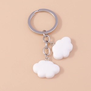 Close-up of white cloud-shaped pendants on a silver metal keychain over pink background