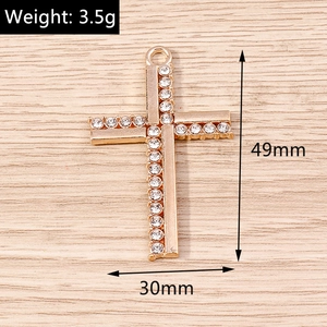 Detailed macro shot of golden cross pendant with crystal inlay showing 49mm size