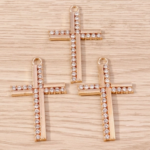Close-up of gold-plated alloy cross pendants with sparkling rhinestones for jewelry making