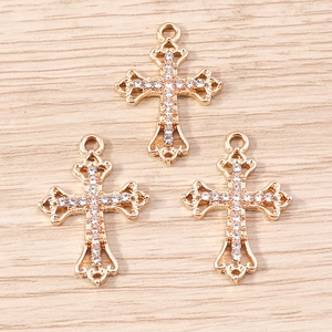 Macro detail of three gold-plated cross pendants with zircons on a wooden surface