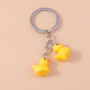 Close-up of cute yellow duck keychains with silver metal rings and detailed PVC charms