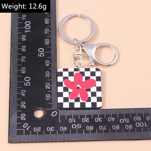 Détail du porte-clés à motif damier et fleur rouge avec fermoir métallique de 12,6g