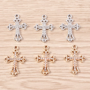 Macro detail of alloy cross pendants with pave-set stones in gold and silver finishes