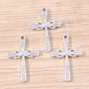 Macro detail of three silver cross pendants with infinity knots and crystal inlay