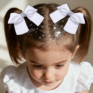 Dettaglio di bambina con fermagli a fiocco bianco con perle e strass luccicanti