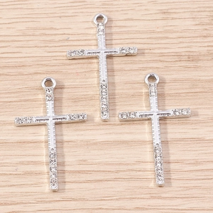 Detailed close-up of three silver alloy cross pendants with clear rhinestones on wood