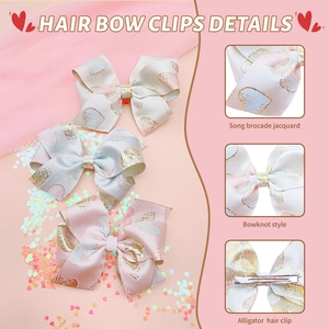 Detail view of Song brocade jacquard bow clips with gold heart patterns and alligator clips