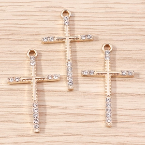 Detailed view of three gold-plated cross pendants with inlaid rhinestones on wood