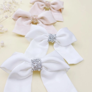 Dettaglio di fermagli a fiocco in raso rosa e bianco con perle eleganti e strass lucenti