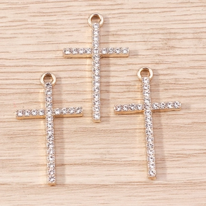 Macro shot of three gold-plated cross pendants with paved zircons on wooden surface