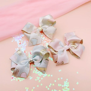 Three Chinese style jacquard bow hair clips with gold heart patterns in soft pastel colors