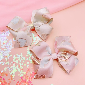 Pink ribbon bow hair clips with gold heart patterns and elegant jacquard satin texture