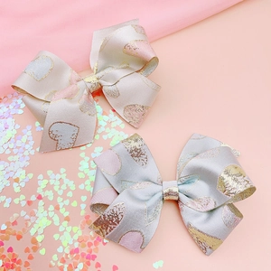 Detail of jacquard silk bow hair clips with gold embroidery and heart patterns