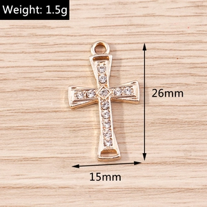 Detailed view of a gold cross pendant with rhinestones measuring 26mm by 15mm dimensions