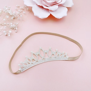 Detail of baby crown headband with rhinestones and white pearls on soft pink background