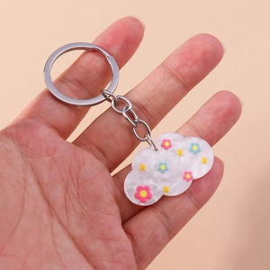 Détail d'un porte-clés nuage en acrylique avec texture nacrée et charmes floraux colorés