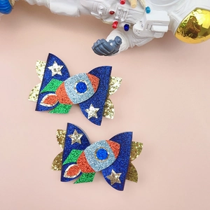 Detail of glitter rocket hair clips for girls with blue bows and stars decoration
