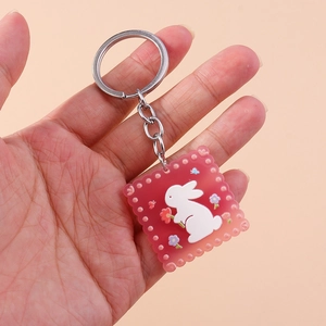 Gros plan d'un porte-clés lapin en acrylique rose avec anneau en métal argenté et gland