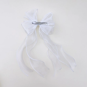Dettaglio della clip a coccodrillo in metallo sulla fiocco in organza bianca