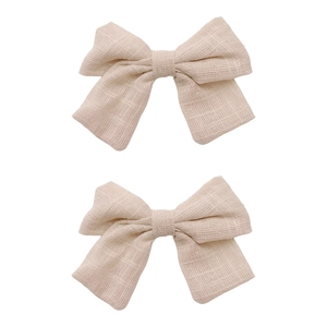Close-up of beige linen bow hair clips showing natural fabric texture and stitching