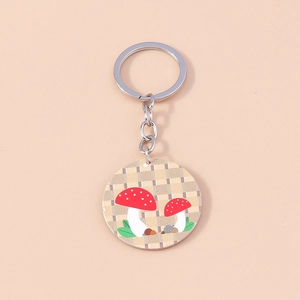 Détail d'un porte-clés rond avec motif de champignons rouges sur fond à carreaux jaunes
