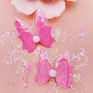 Close-up of pink glitter bow hair clips with transparent bunny ears and star sequins