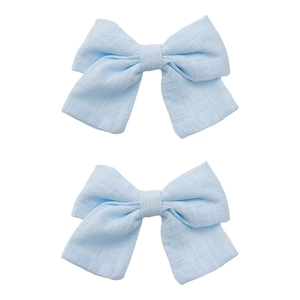 Detail of light blue linen bow clips with natural fabric texture and handmade design