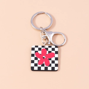 Gros plan du porte-clés en damier avec charme fleur rouge et anneau en métal argenté
