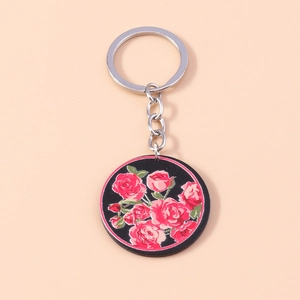 Détail d'un porte-clés floral rond avec des roses rouges vintage sur fond noir et anneau