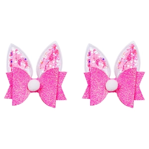 Close-up of pink glitter bow hair clips with plush ball and transparent bunny ears