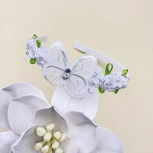 Détail du serre-tête papillon en dentelle avec fleurs en satin et perles