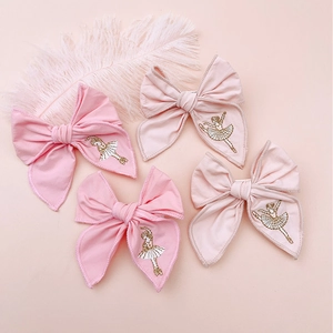 Detail of four handmade ballet girl hair clips in pink fabric with golden embroidery