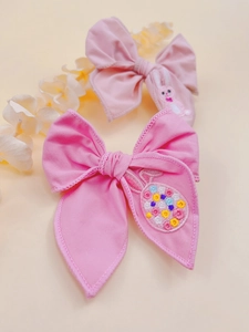 Detail of pink embroidered hair clips featuring a bunny and Easter eggs on fabric