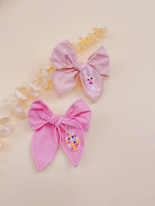 Detail of pink embroidered bow hair clips featuring cute rabbit and easter egg patterns