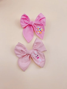 Detail of pink fabric bow hair clips with cute embroidered rabbits for girls